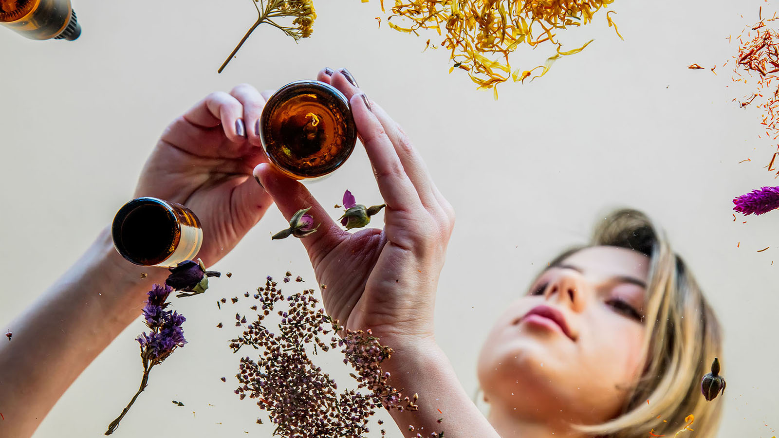 Woman preparing fragrance oil from different ingredients.