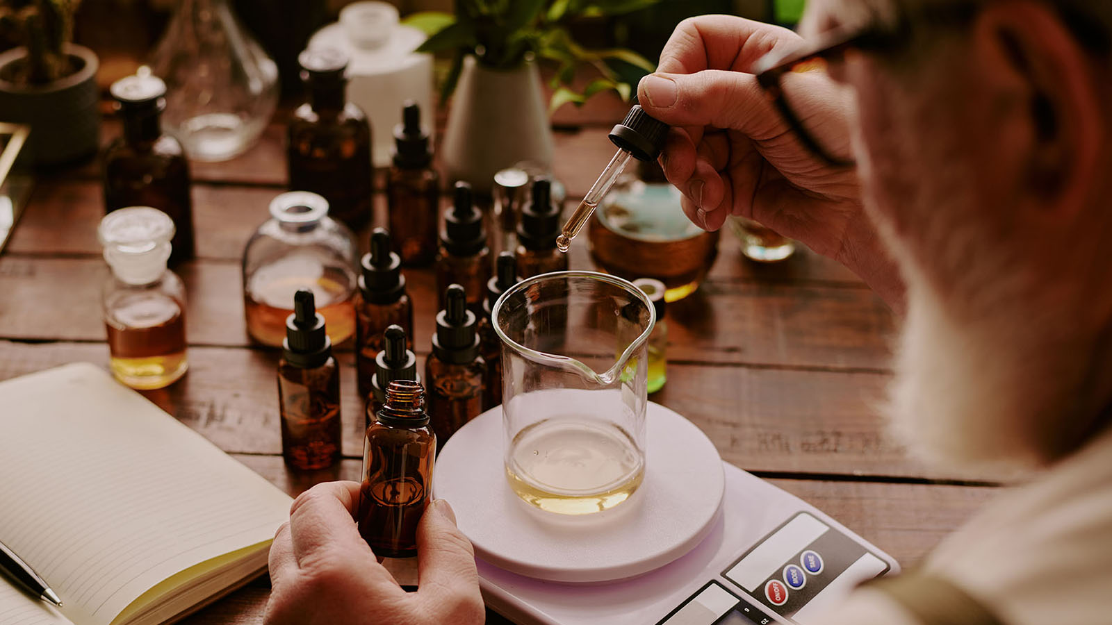 Fragrance chemist adding fragrance oil and weighing it.